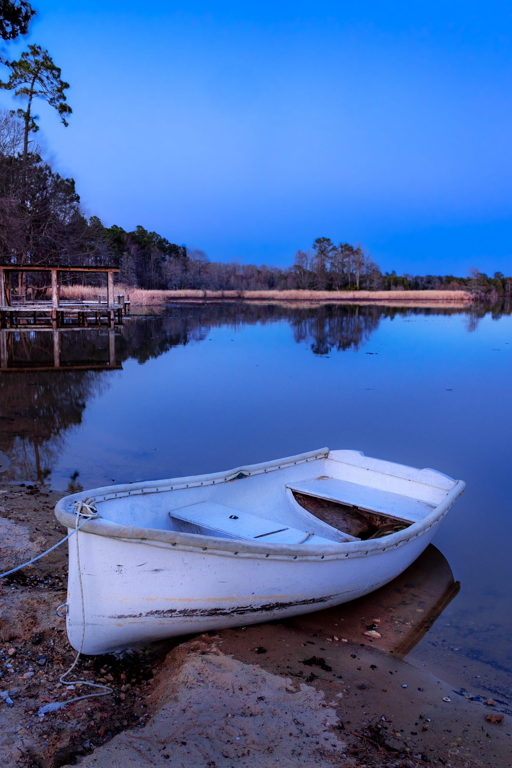 A camp dinghy rests at twilight, reminiscent of an artist’s still life.