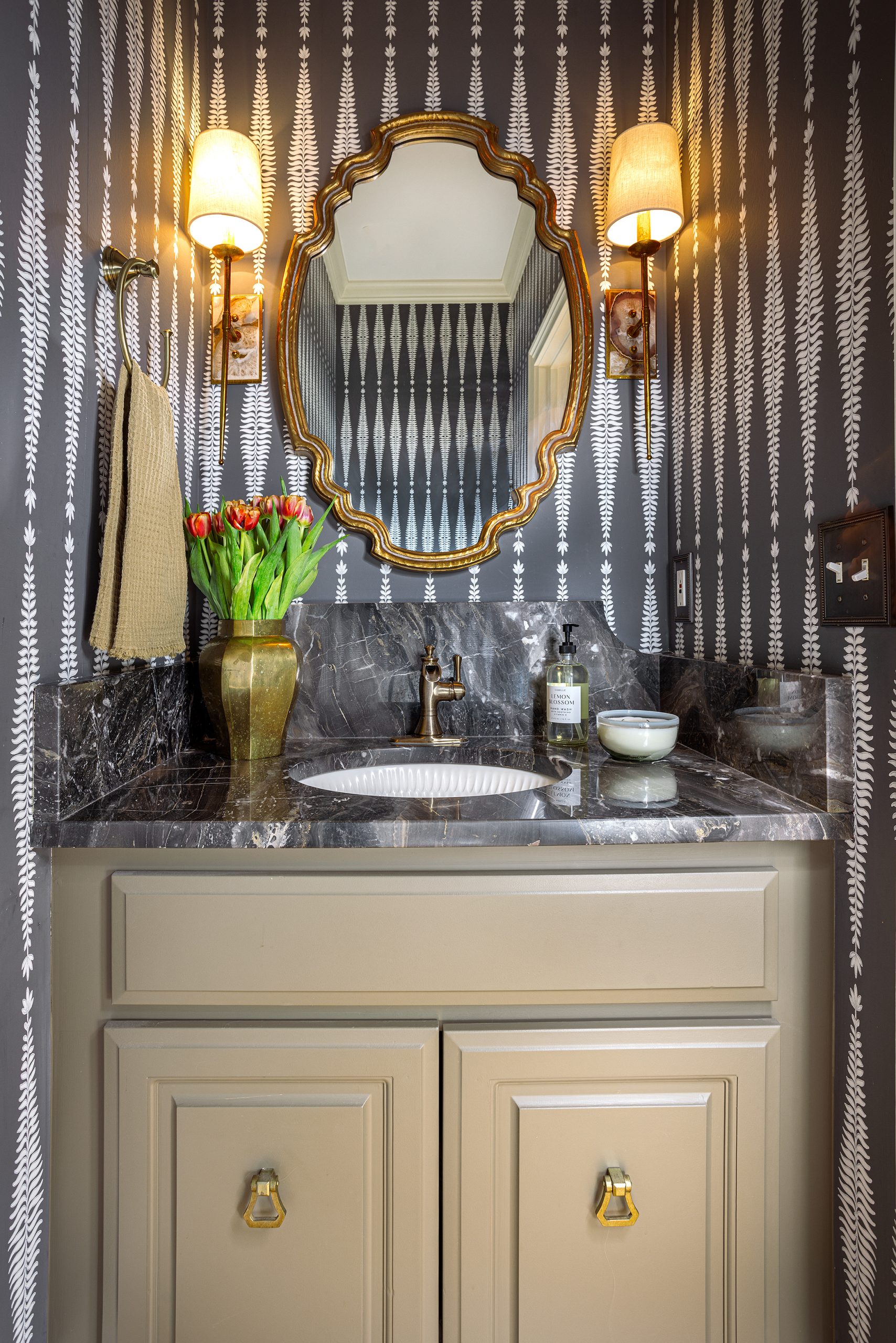 The powder room was transformed with a classic dark gray Schumacher wallpaper and black marble countertops — very chic! 
