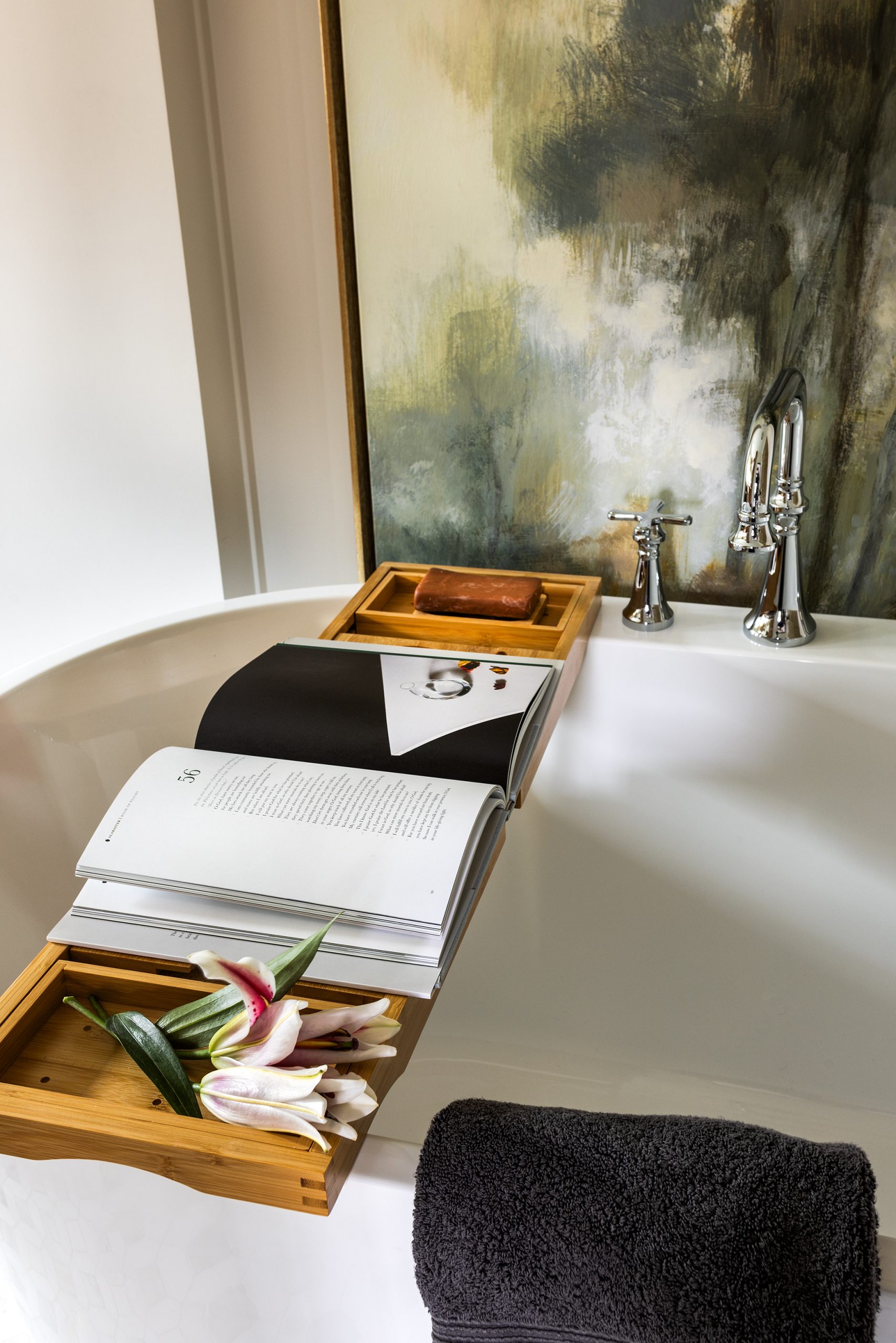 Dark mahogany double doors connect the primary bedroom suite to the bath, opening to a soaking tub that perches beneath a tall abstract painting.
